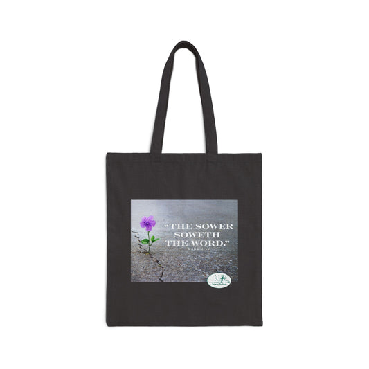 Black tote bag with a purple flower and text on a white background that says The Sower soweth the Word.