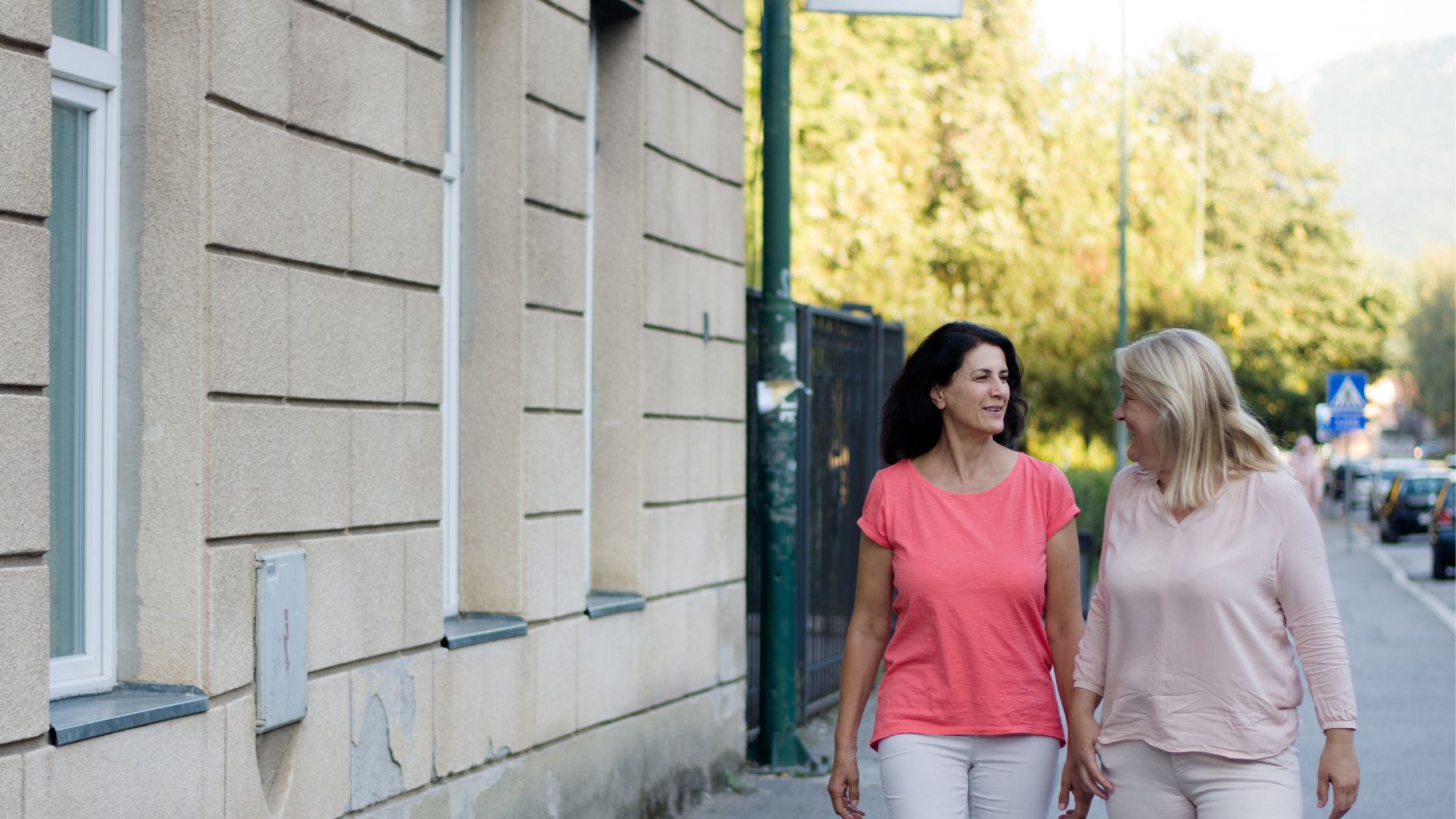 Two women walking on a sidewalk next to a building